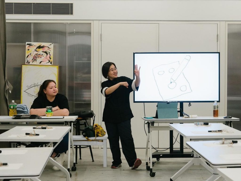 KK, one of our HKSL Consultants and Deaf artist, signs expressively to the participants of the art workshop for the hearing.